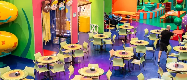 Salão da XVentura montado para a festa, com mesas infantis e a área de brinquedos ao fundo